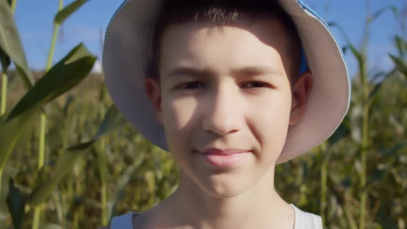 Portrait of a Funny Boy in a Hat on a Cornfield Looking at the Camera and Smiling