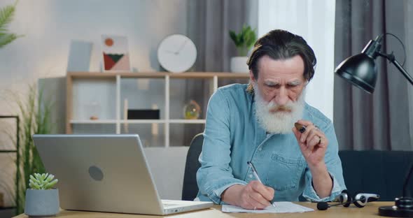 Mature Man Working on Computer at Home and Smoking a cigar