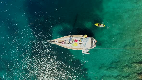 Aerial view of paddle board next to boat anchored on the coast of Varko, Greece.