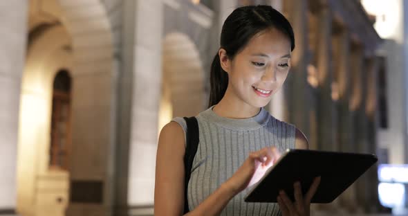 Woman use of tablet computer in city at night 