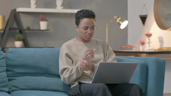 African Woman with Laptop Having Wrist Pain on Sofa