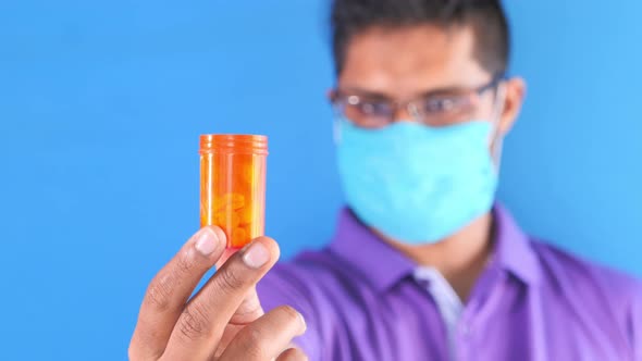  Young Man in Face Mask Holding Pill Container 