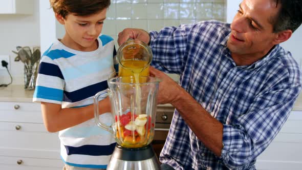 Father and son preparing smoothie in kitchen