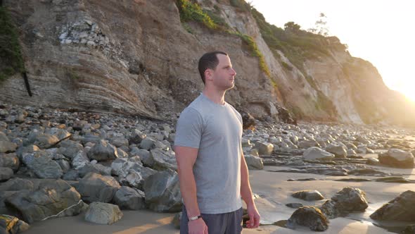 A strong man athlete preparing for a morning run and a fitness workout on the beach at sunrise in Sa