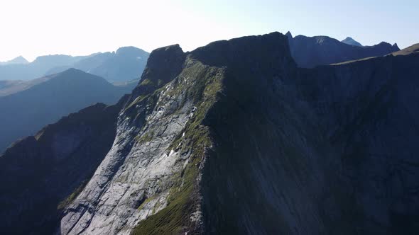 Flying over the chine of a mountain (Reinebringen, Norway) looking at the mountains in the backgroun