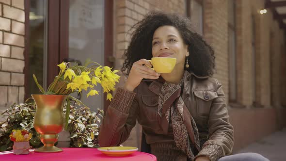 Portrait of Stylish Young African American Woman Enjoys Aroma and Taste of Hot Coffee