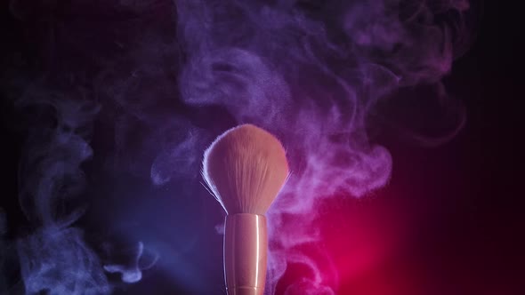 Two Makeup Brushes Touch Each Other to Form an Intricate Swirl of Cosmetic Powder Particles