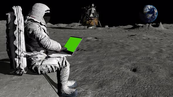 Astronaut on the Moon Typing on a Laptop with a Green Screen alt
