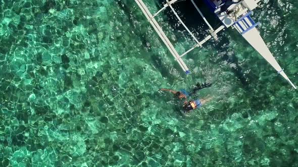 Aerial view of two people snorkeling in turquoise water in Panagsama Beach.