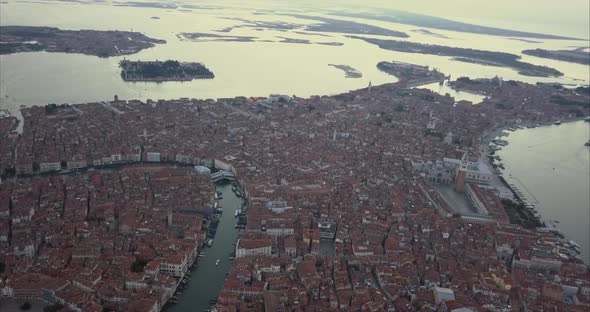 Wide aerial descending shot of Canal Grande and Ponte di Rialto from above at dusk, Venice, Italy