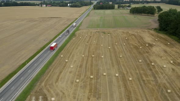 Transportation Trucks On The Road Driving Through Farm Fields with Haystacks