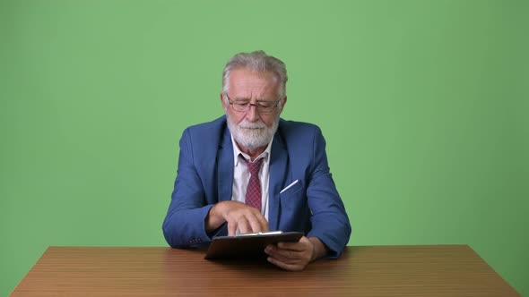 Handsome Senior Bearded Businessman Against Green Background