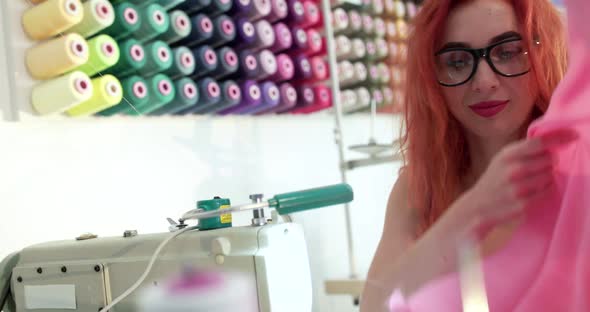 Portrait of Happy Dressmaker Using a Sewing Machine to Sew the Clothes in Studio