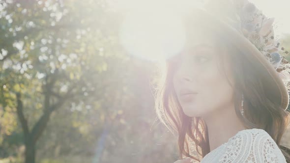 Young beautiful woman in white dress and brown hat posing. Attractive fashion model with loose hair.