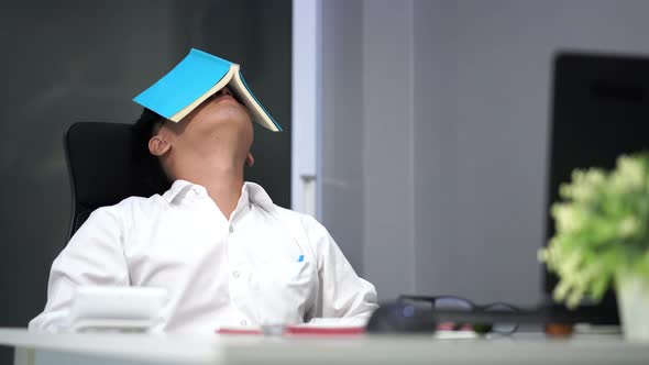 young stressed man studying with book and laptop