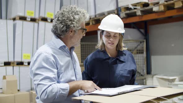 Focused Supervisor and Female Employee Talking in Warehouse