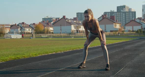 Athletic Blonde Woman Finishing Running and Bending Over To Catch Her Breath