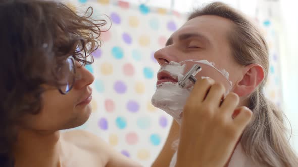 Close Up of Young Gay Couple Shaving Together in Bathroom
