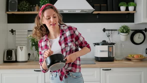 Carefree happy young woman housewife dancing alone cooking meal