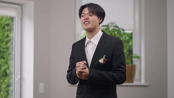 Cheerful Asian Groom with Toothy Smile Showing Victory Gesture Looking Away Laughing