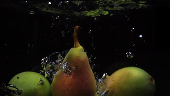 Three Pears Falls Into the Water with Splashes and Bubbles in Slow Motion