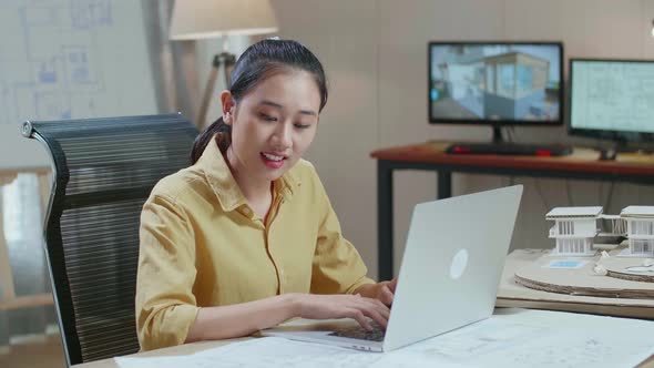 Asian Woman Engineer Typing On A Laptop At The Architectural Office