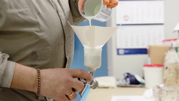 Close Up View of Pouring Light Blue Paint Into Spray Gun