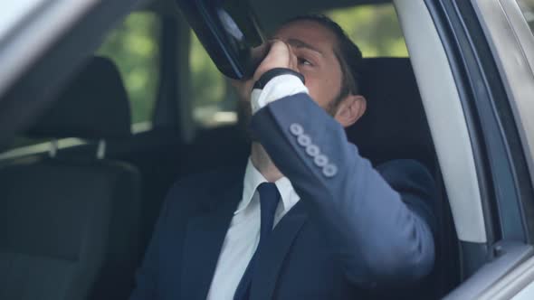 Portrait of Young Handsome Man Drinking From Bottle Sitting on Driver's Seat in Car