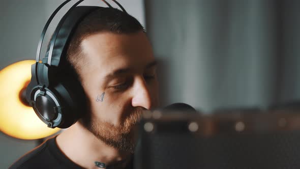 Caucasian Attractive Man with Headphones Singing in a Microphone in Studio Closeup Indoor Studio