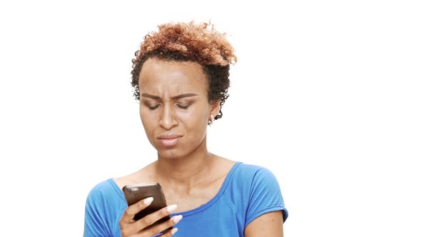 Upset Young Beautiful African Girl Looking at Phone Over White Background