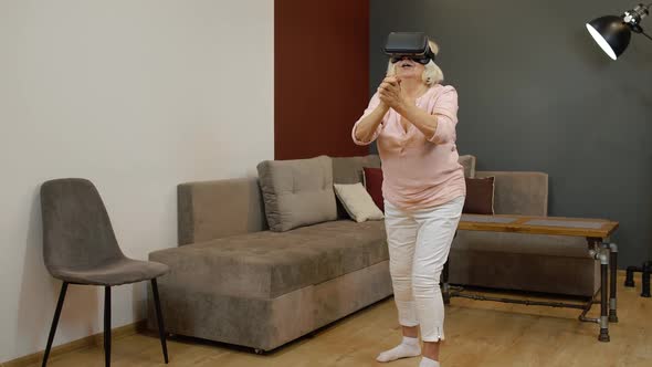 Senior Grandmother Woman in Virtual Headset Glasses Watching Amazing 3D Video in VR Helmet at Home
