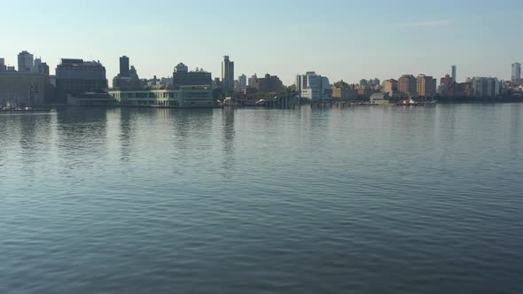 A low angle drone shot over a calm Hudson River at sunrise. The camera dolly in over the water flyin