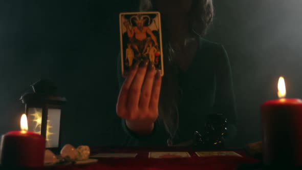 A Tarot Card in the Hands of a Fortune Teller Depicting Figures of Naked Women and a Devil