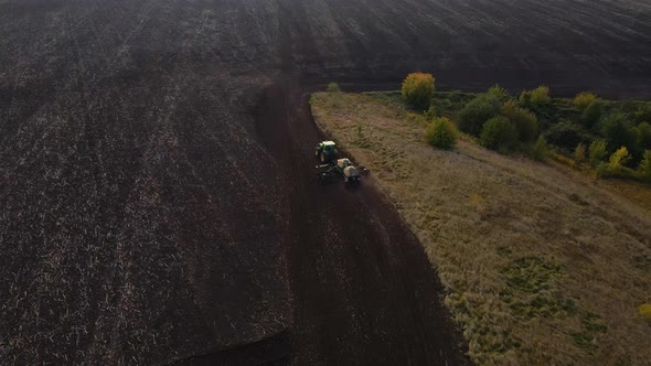 Aerial view, drone view of green tractor with plough working on a field,