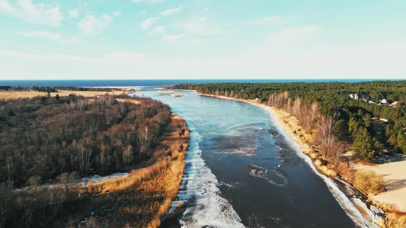 Spring Aerial View Over River Joining Baltic Sea with Melting Ice and Snow