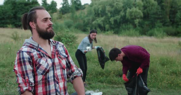 Baffled Man Looks and Crosses Hands at Camera at a Youngs Collecting Garbage