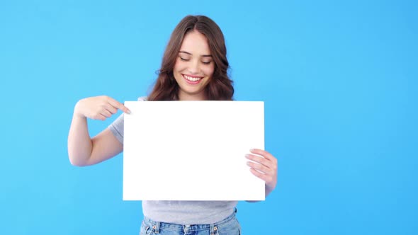 Beautiful woman holding blank placard on blue background