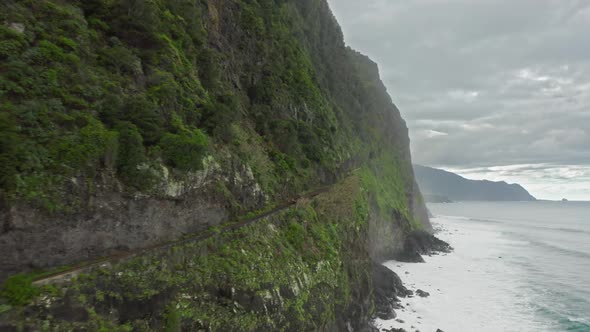 Aerial View of Sheer Cliffs with Scenic Waterfall and Lush Vegetation