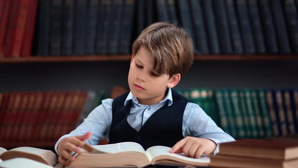 Trendy Focused Male Schooler Reading Vintage Paper Textbook Turning Pages Doing Homework at Library