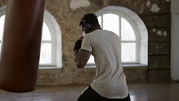 Afro American Boxer Punching the Heavy Bag in the Gym