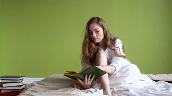 Girl Sitting On The Bed And Reading Book