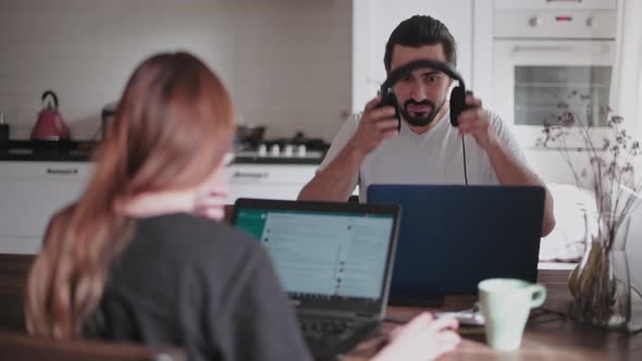 A young man and a young girl are working in front of laptops in their bright apartment.