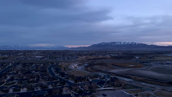 A suburban community with snow-capped mountains and a lake in the distance - aerial flyover
