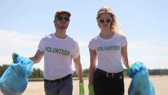 Two Volunteer Family Recycle Plastic Bottle Man and Woman Wear Tshirt and Hold Bags with Trash Spbi