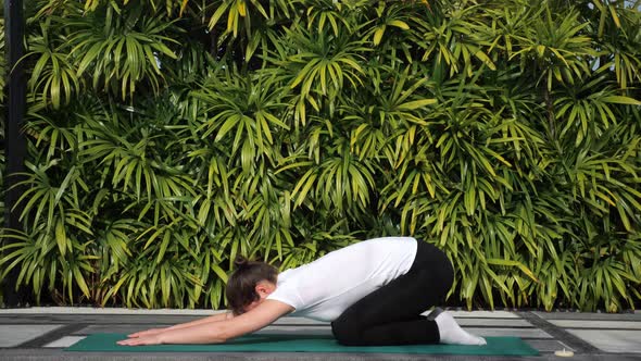 Woman Doing Stretching on a Background of Green Foliage