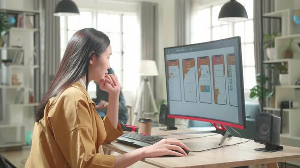 Asian Female Mobile Application Developer Thinking While Works With Graphics On Computer In Office