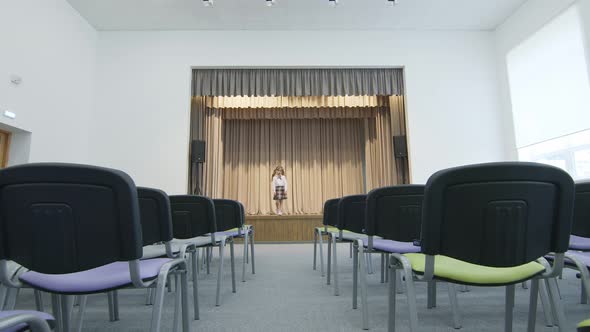 Little Girl on Stage in a Hall Without People. the Girl Revolves Around Herself