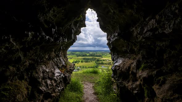 Time lapse of rural farming landscape with grass fields and hills during a dark cloudy day viewed fr