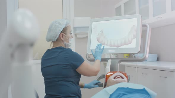 Girl Doctor Dentist Demonstrates a 3D Model of Teeth on a Touch Monitor