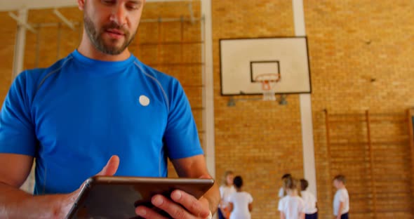 Basketball coach using digital tablet in basketball court at school 4k